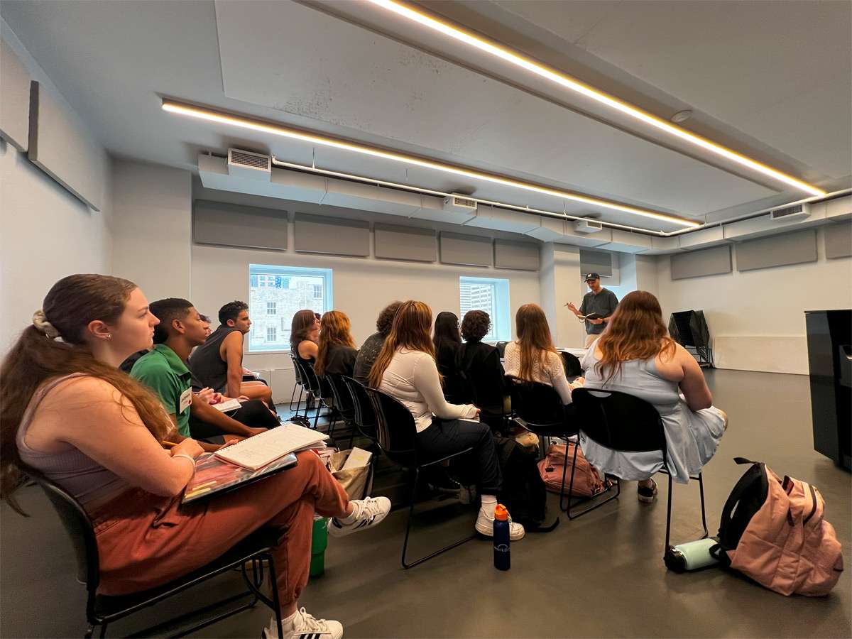 A group of students sitting in a classroom at the Open Jar Institute learning about the business of Broadway